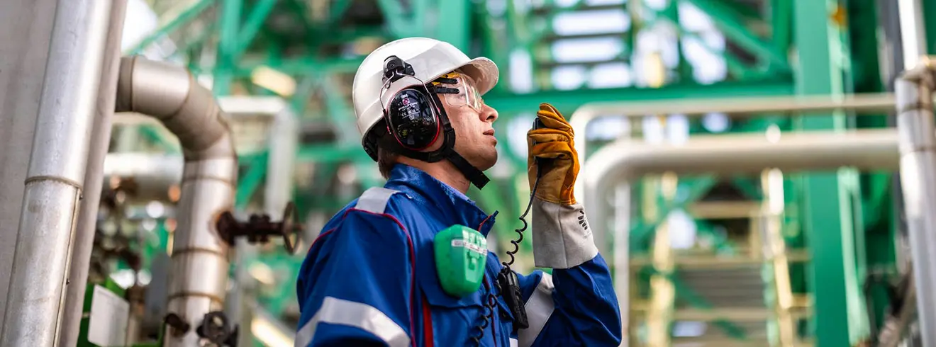 A professional wearing PPE remotely communicates information in an industrial environment