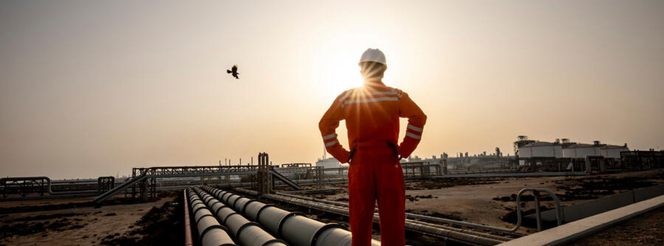A person wearing PPE observing an industrial facility